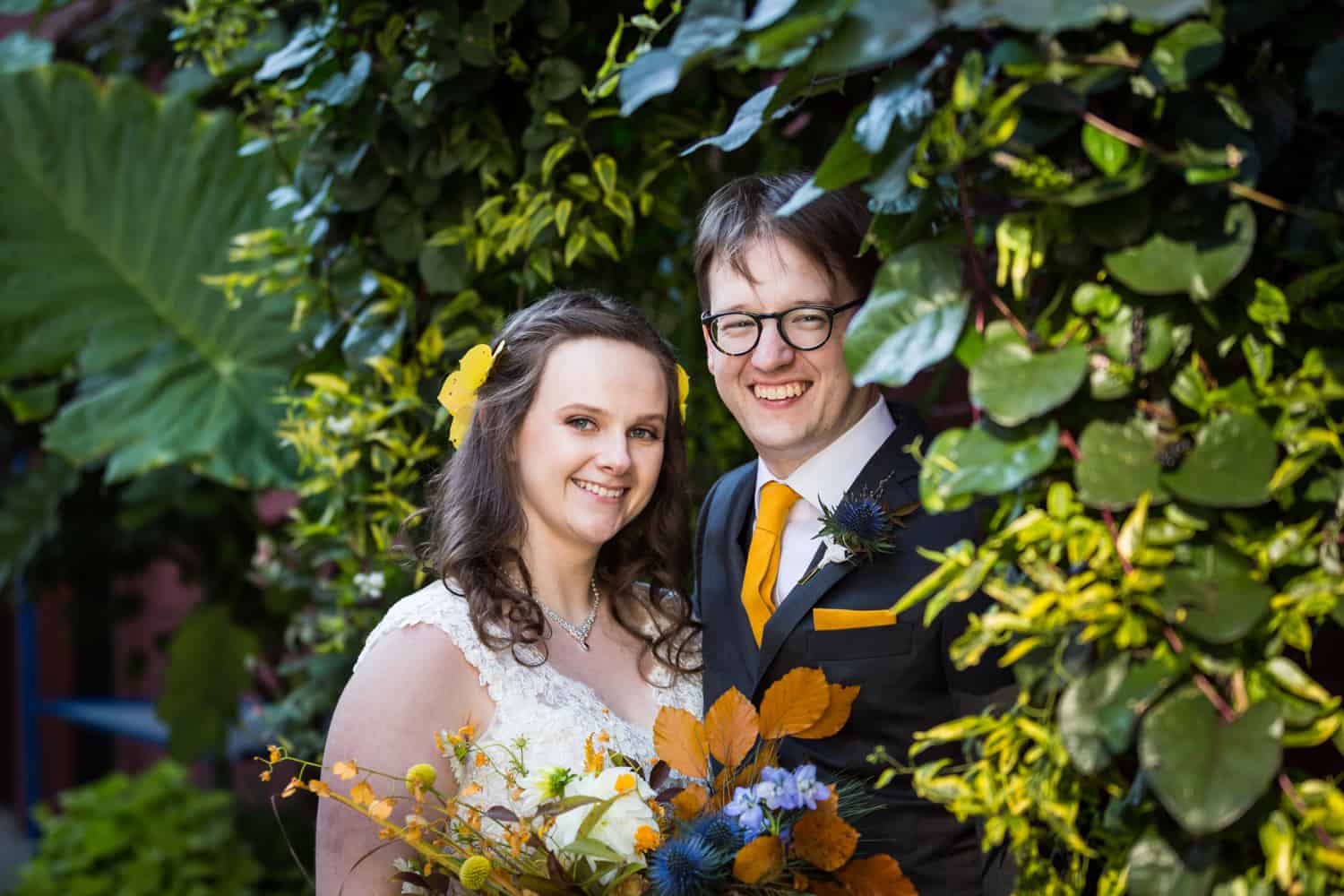Bride and groom surrounded by plants for an article on Covid-19 wedding planning