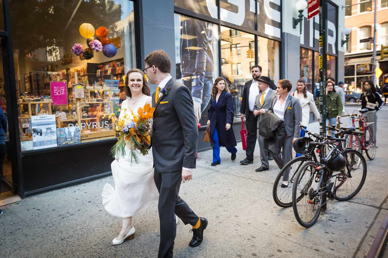 Bride and groom walking in front of bridal party on NYC sidewalk