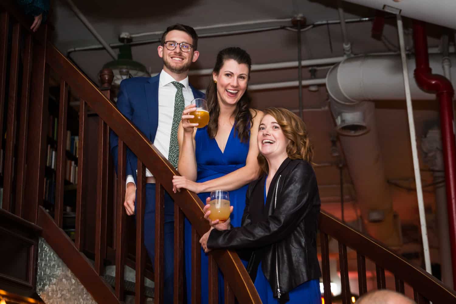 Three guests on stairs laughing at a Housing Works Bookstore Cafe wedding