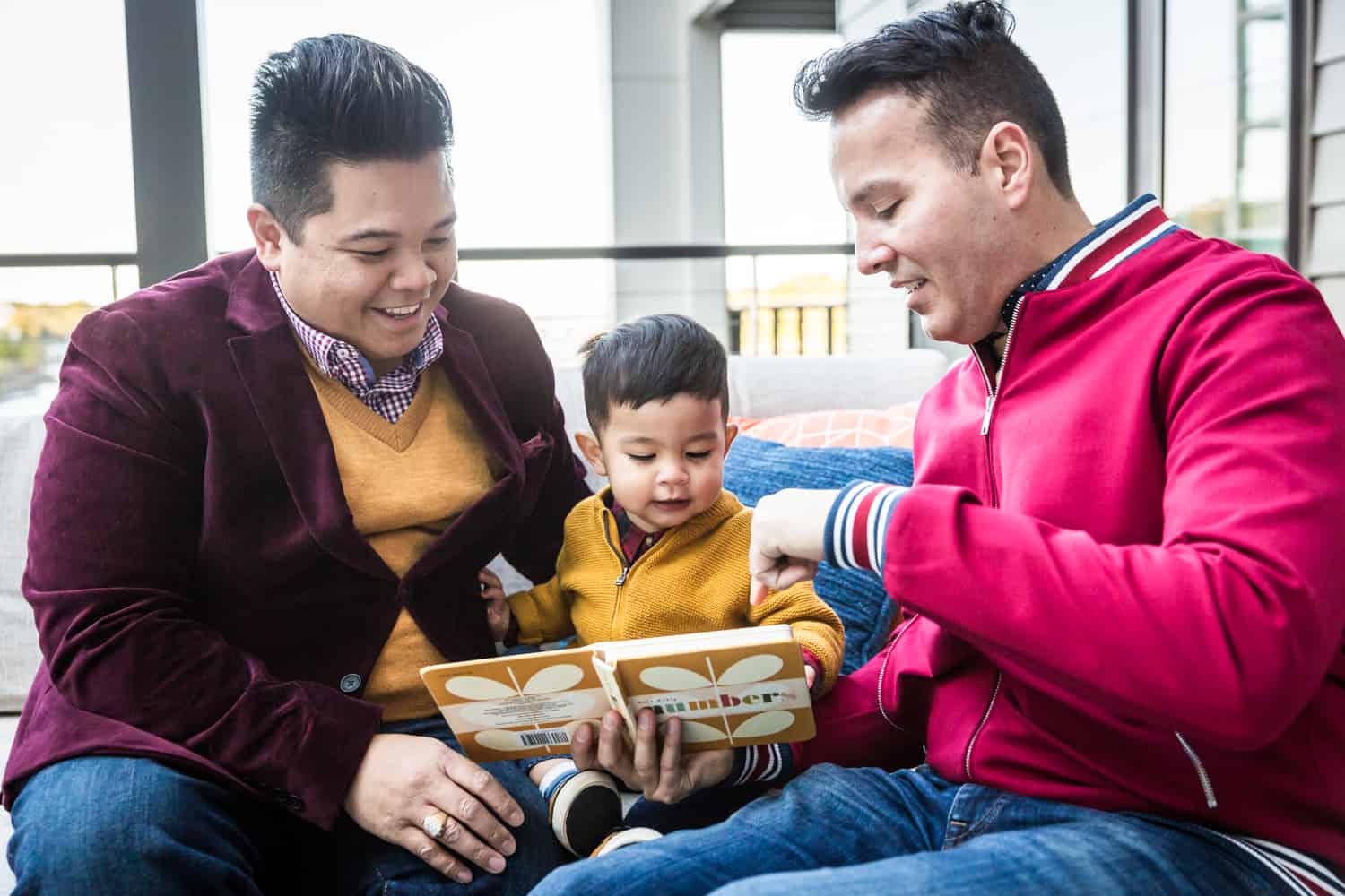 Two fathers reading with little boy during a Great Neck family portrait session