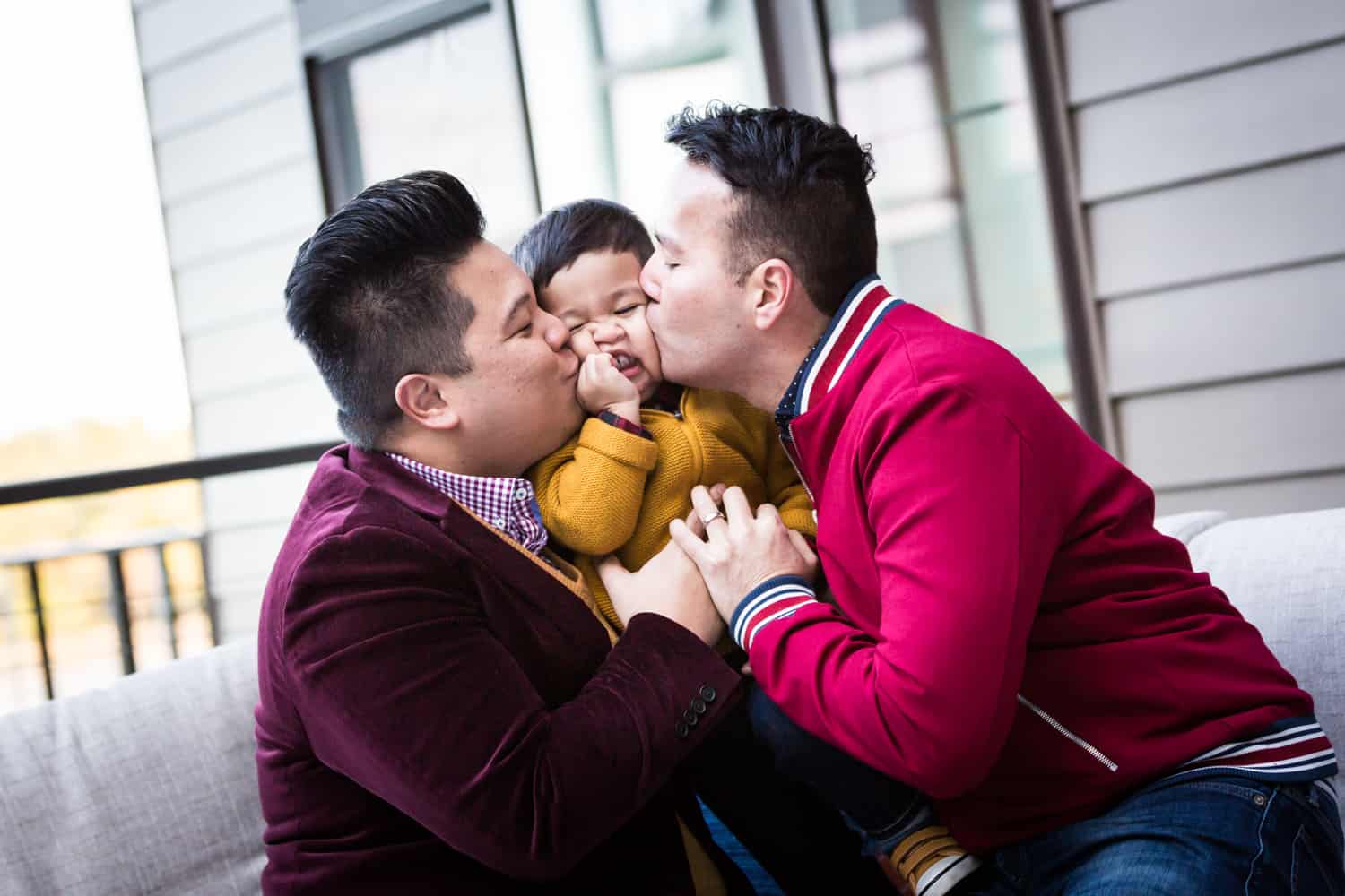 Two gay fathers kissing little boy on the cheeks