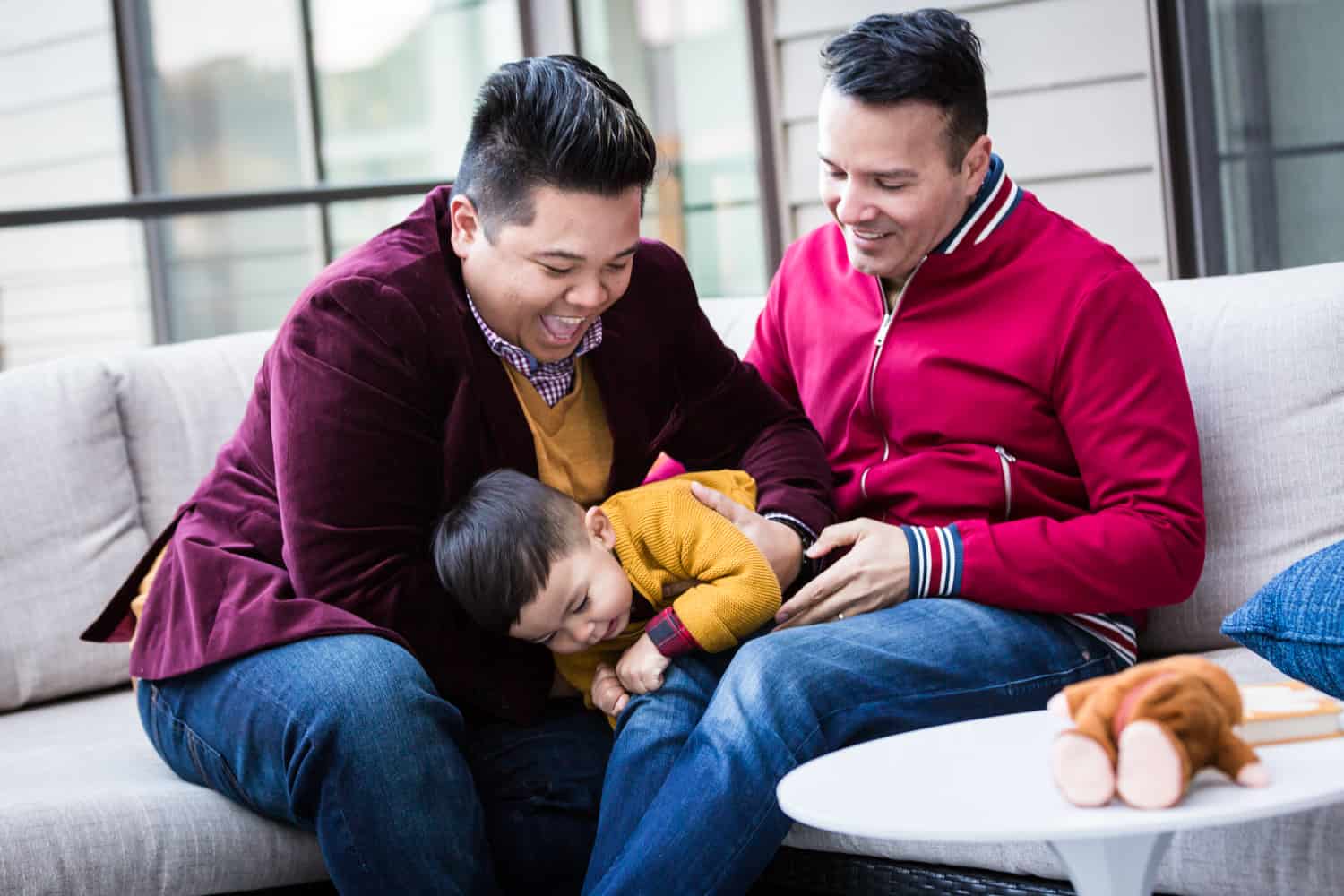 Little boy squirming in between two fathers during a Great Neck family portrait session
