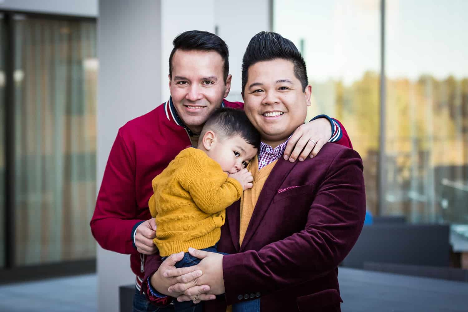 Two gay fathers holding little boy during Great Neck family portrait session