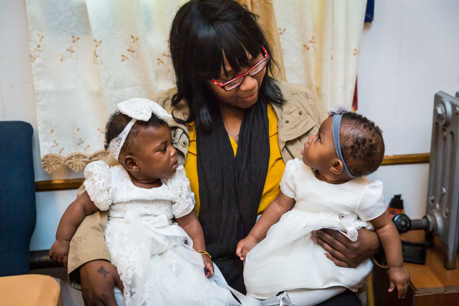 African American woman holding two little babies on her lap before Jamaica christening