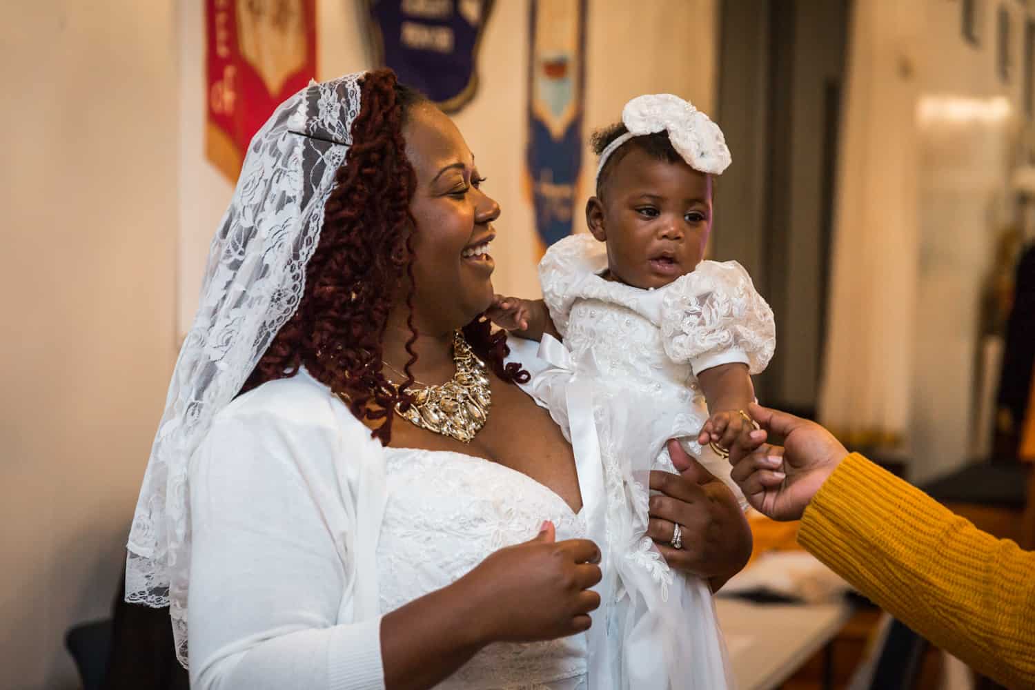 Smiling mother holding little baby before Jamaica christening