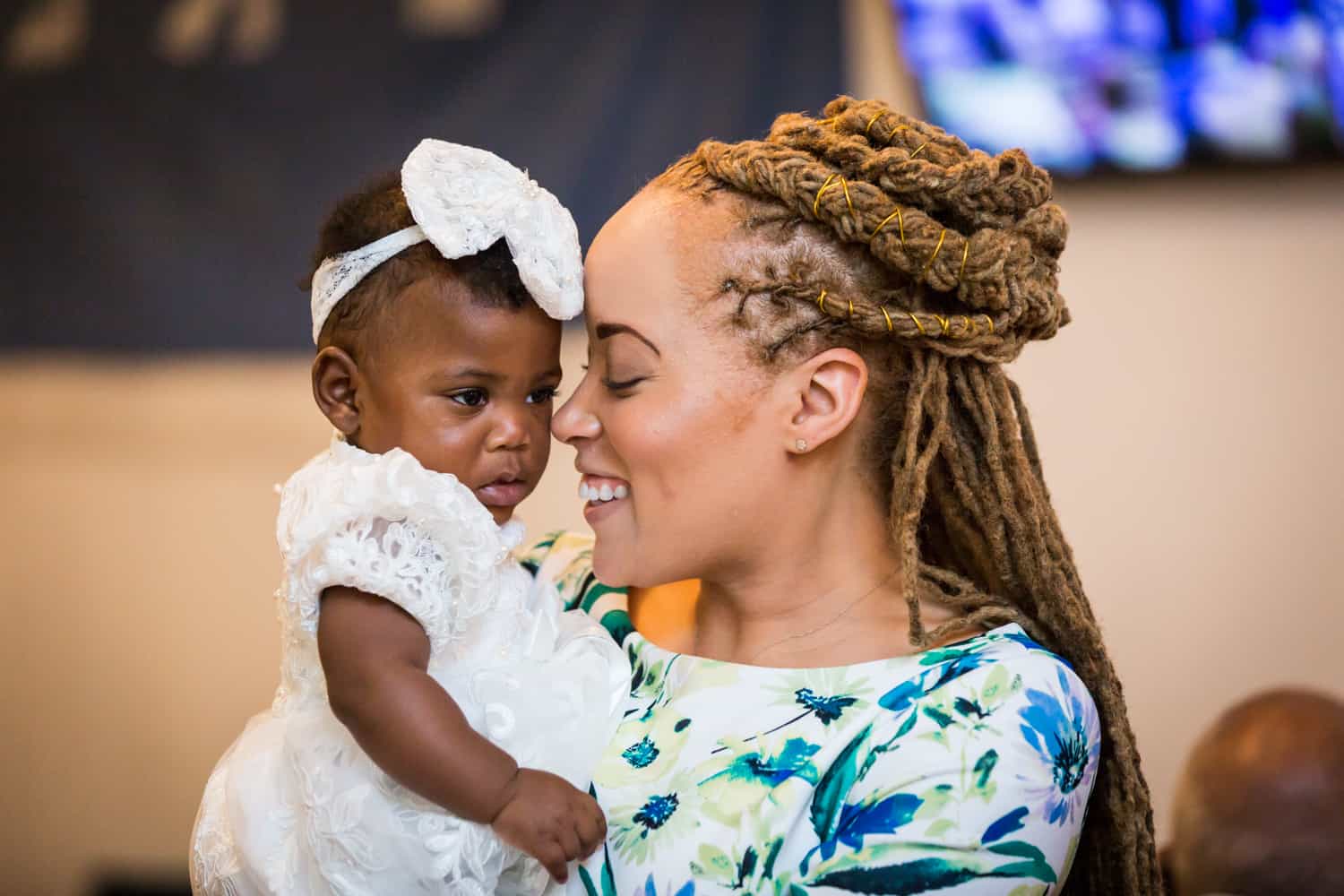 Woman with braided hair nuzzling with little baby girl