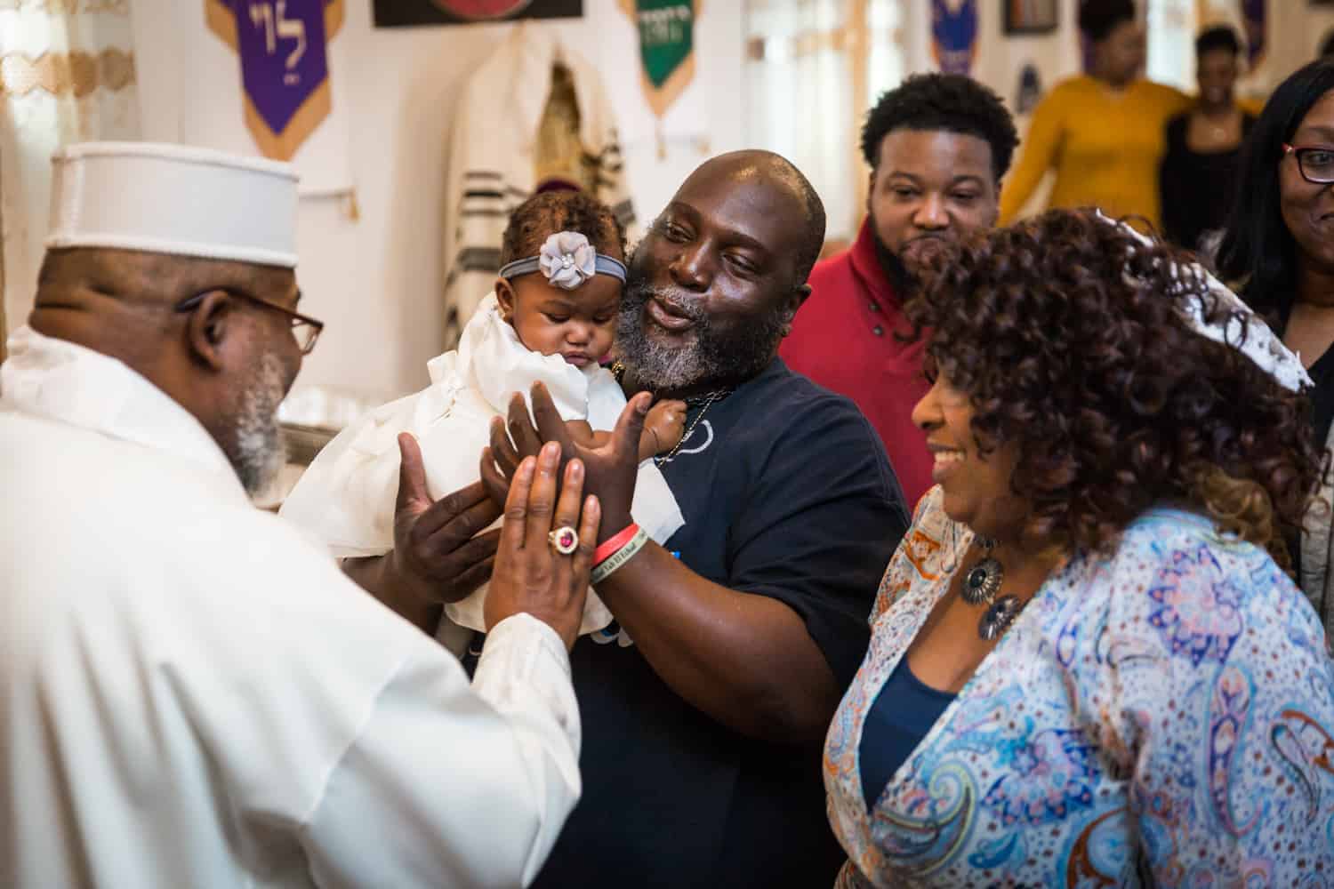 Little baby held by family members during Jamaica christening blessing