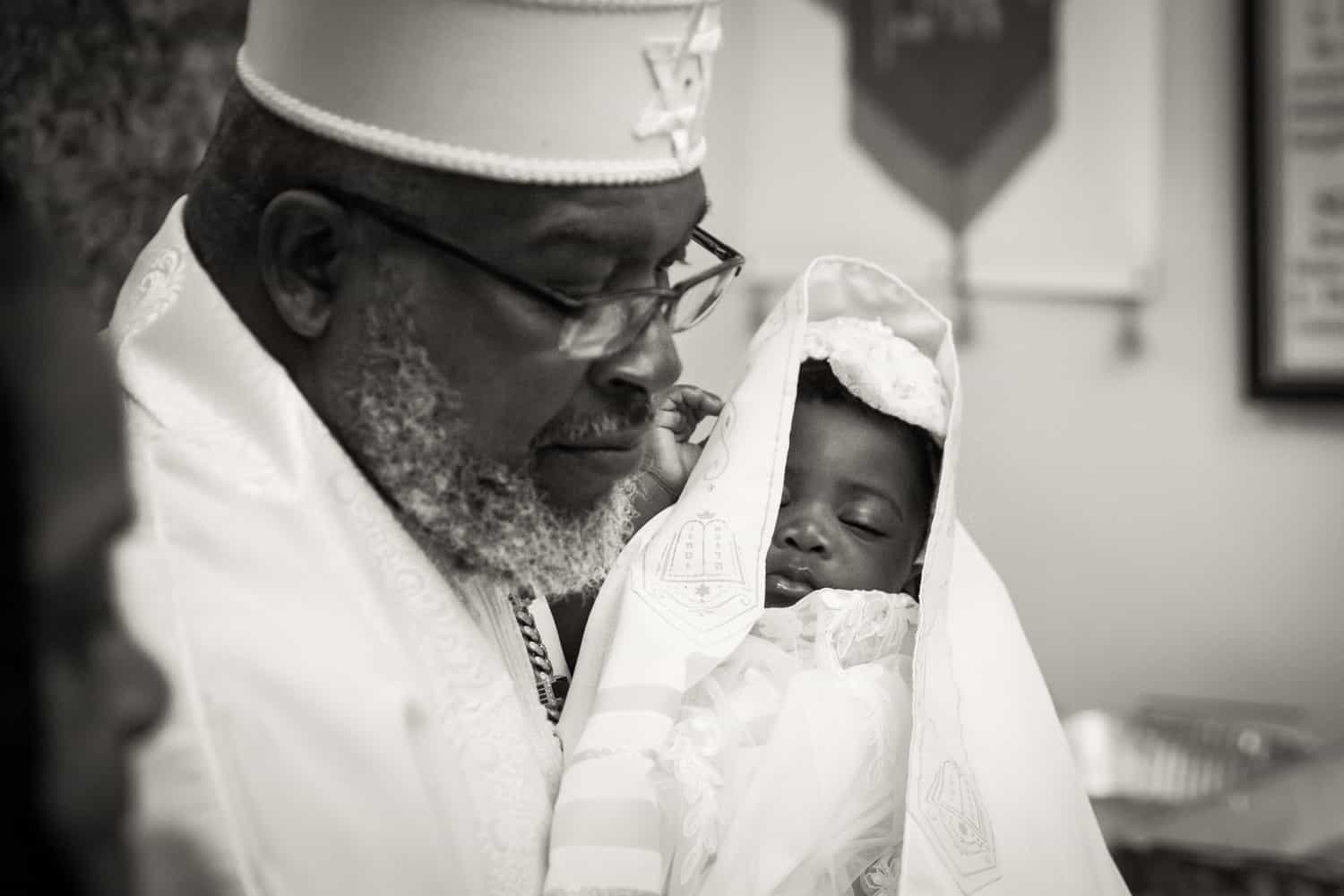 Black and white photo of pastor holding sleeping baby