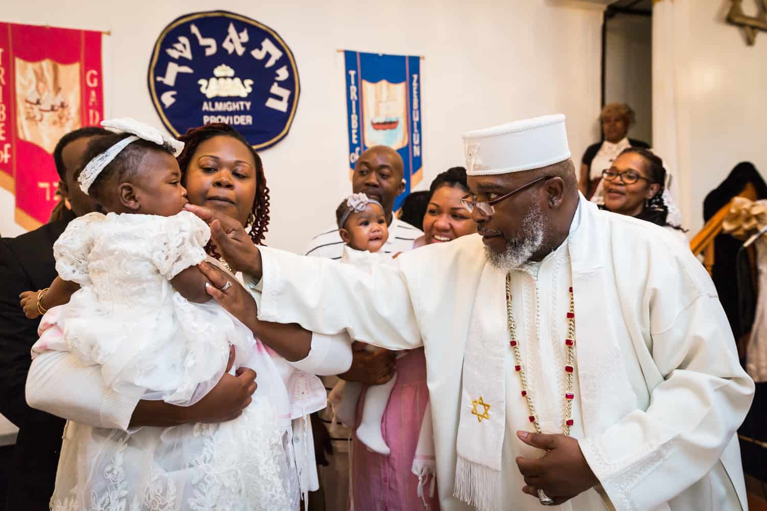 Pastor putting finger in baby's mouth during Jamaica christening