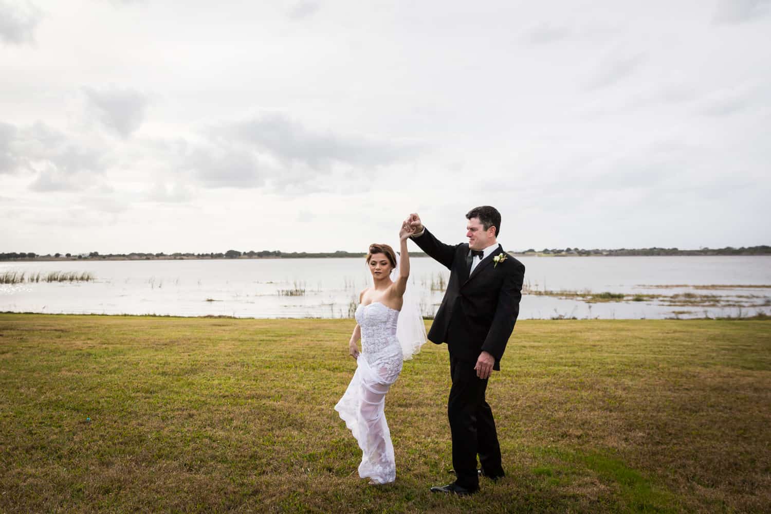 Bride and groom dancing in front of lake for an article on wedding cost cutting tips