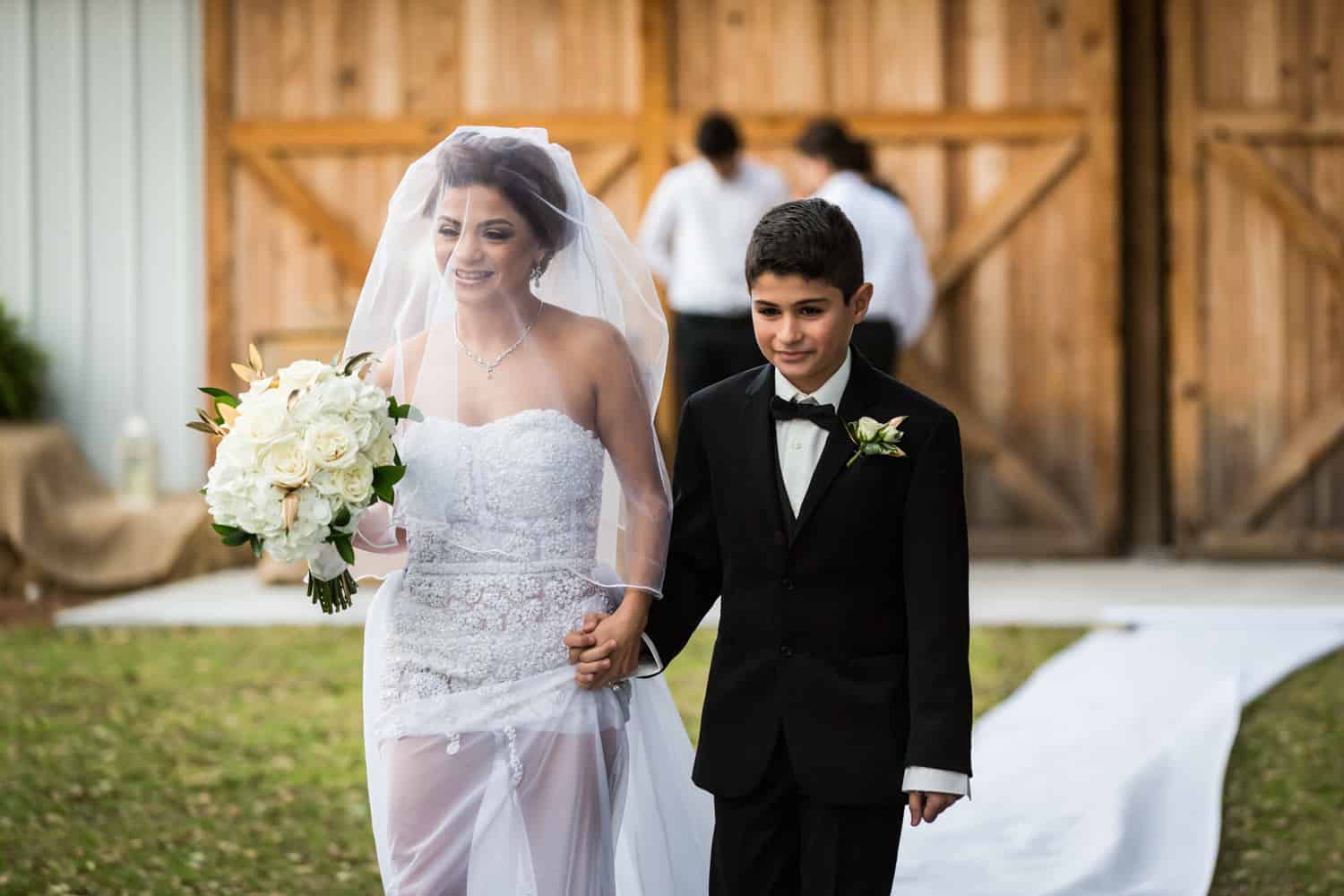 Bride and son walking down aisle during ceremony for an article on wedding cost cutting tips
