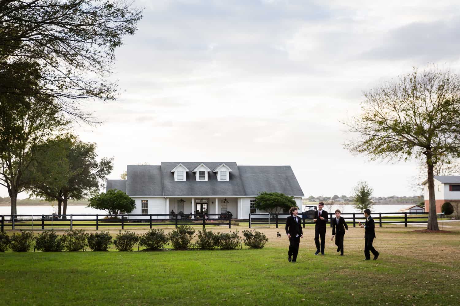 Young groomsmen playing outdoors in front of house for an article on wedding cost cutting tips