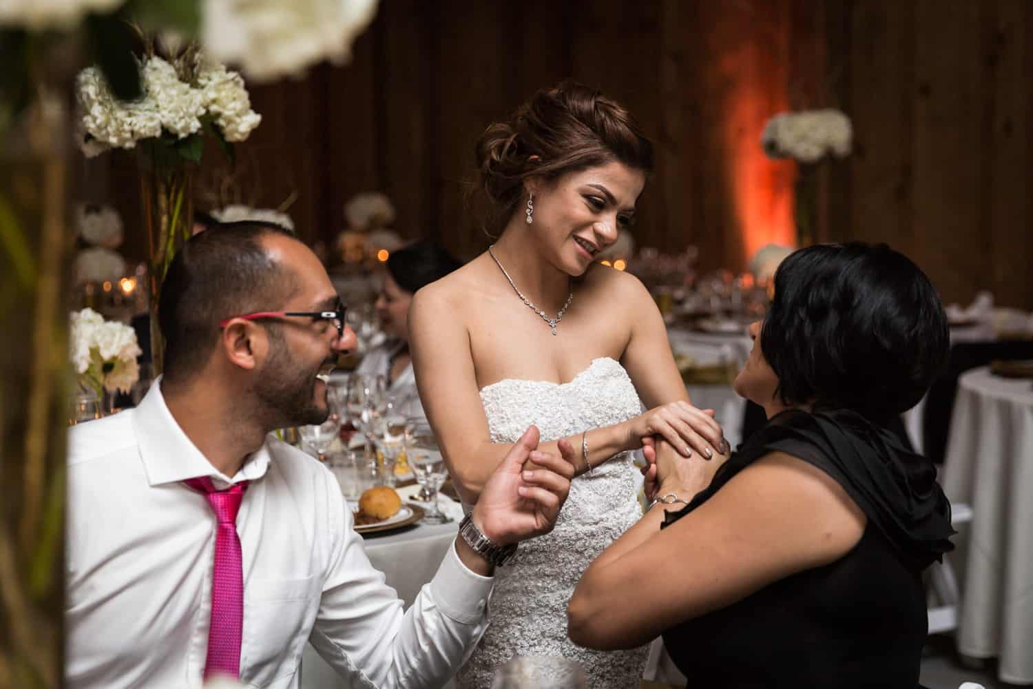 Bride chatting with couple at table 