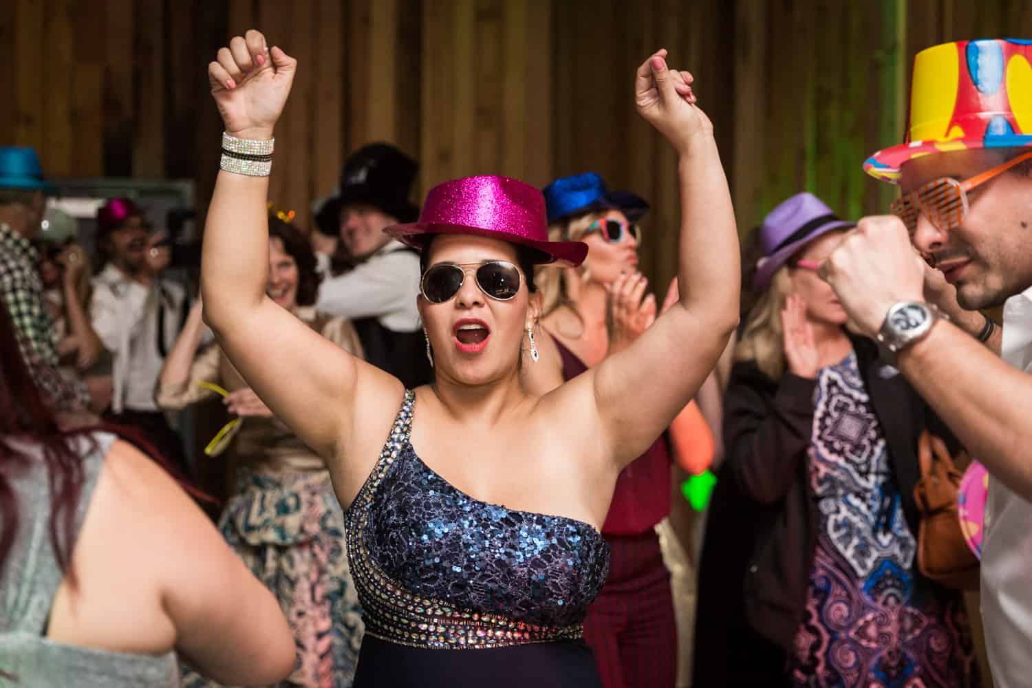 Woman wearing hat and sunglasses dancing with hands in air