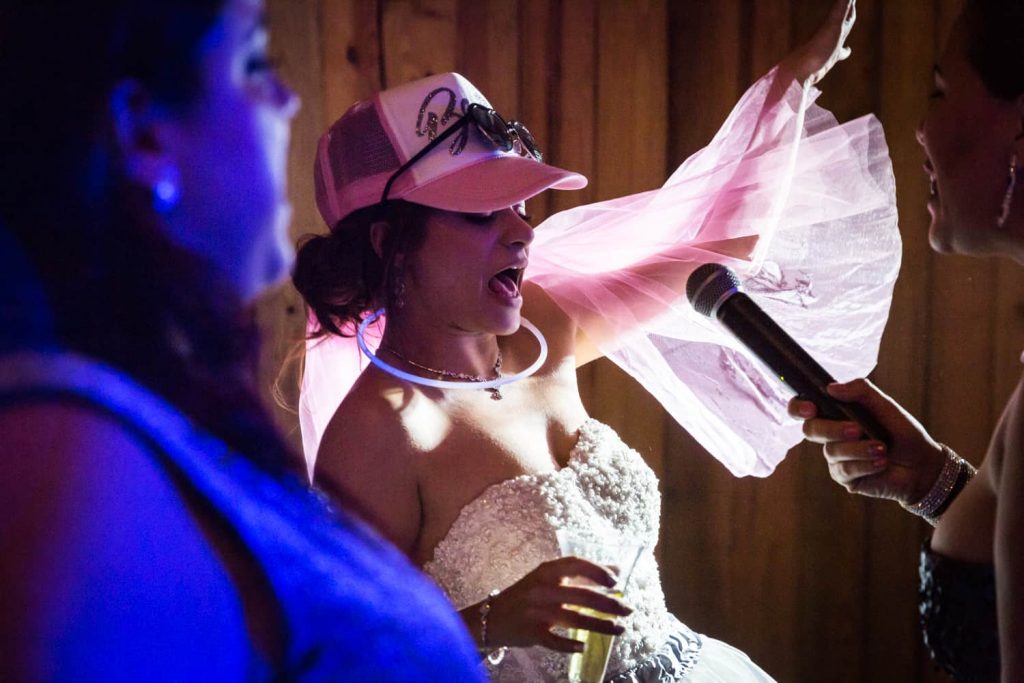 Bride wearing trucker hat and singing into microphone