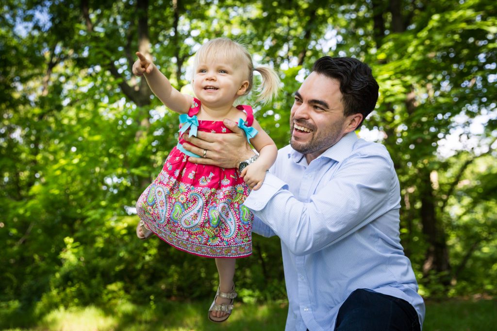 Father holding up little girl in Forest Park during family portrait session