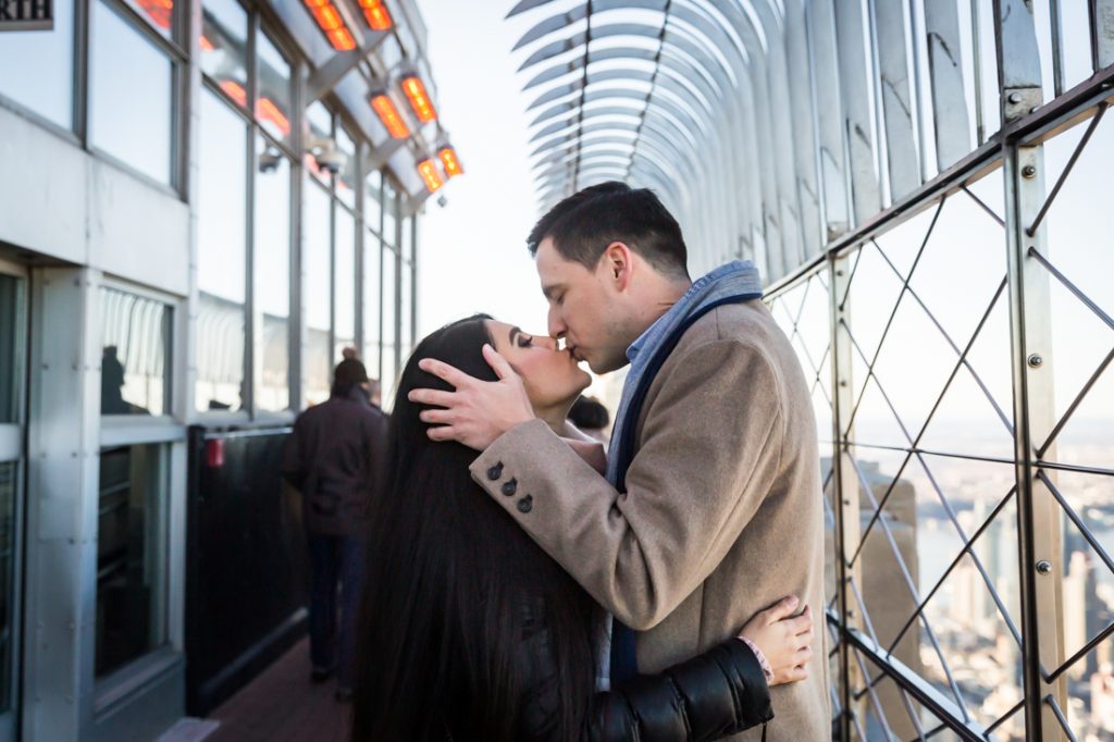 Couple kissing after proposal on top of the Empire State Building