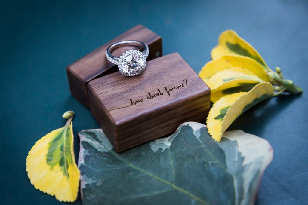 Close up of engagement ring, wooden box, and leaves