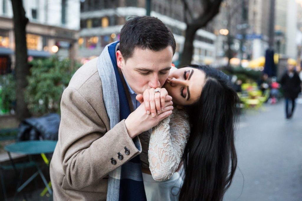 Man kissing woman's hand with engagement ring
