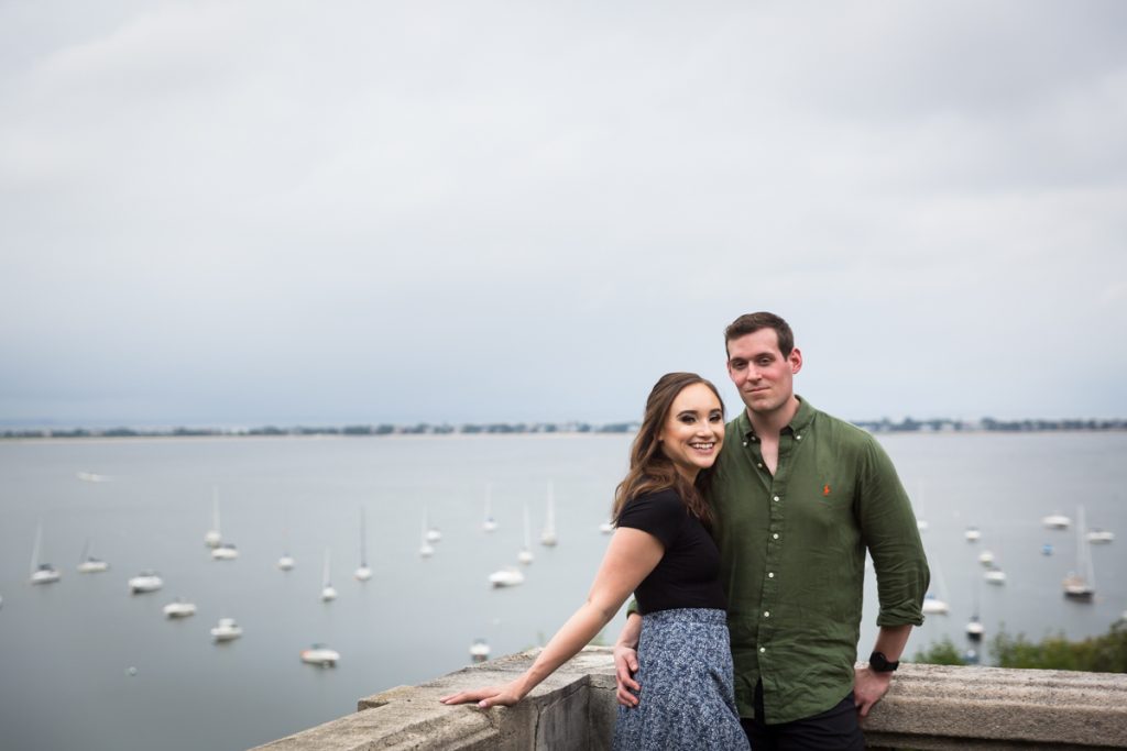 Couple in corner of railing with view of boats and bay in background