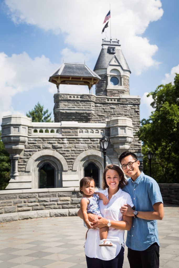 Parents holding toddler in front of castle turret during Belvedere Castle family portrait in Central Park