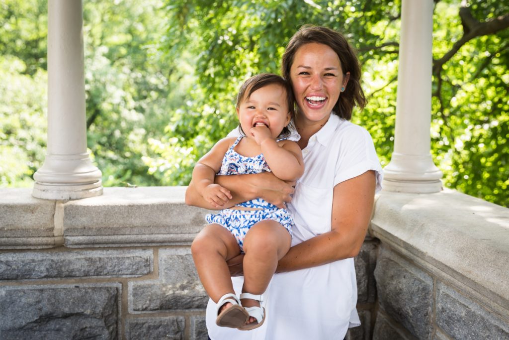 Mother holding smiling baby during Belvedere Castle family portrait in Central Park