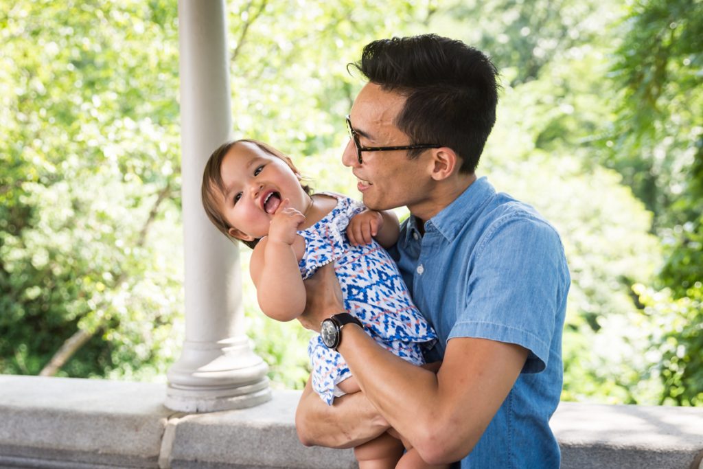 Father holding smiling baby during Belvedere Castle family portrait in Central Park