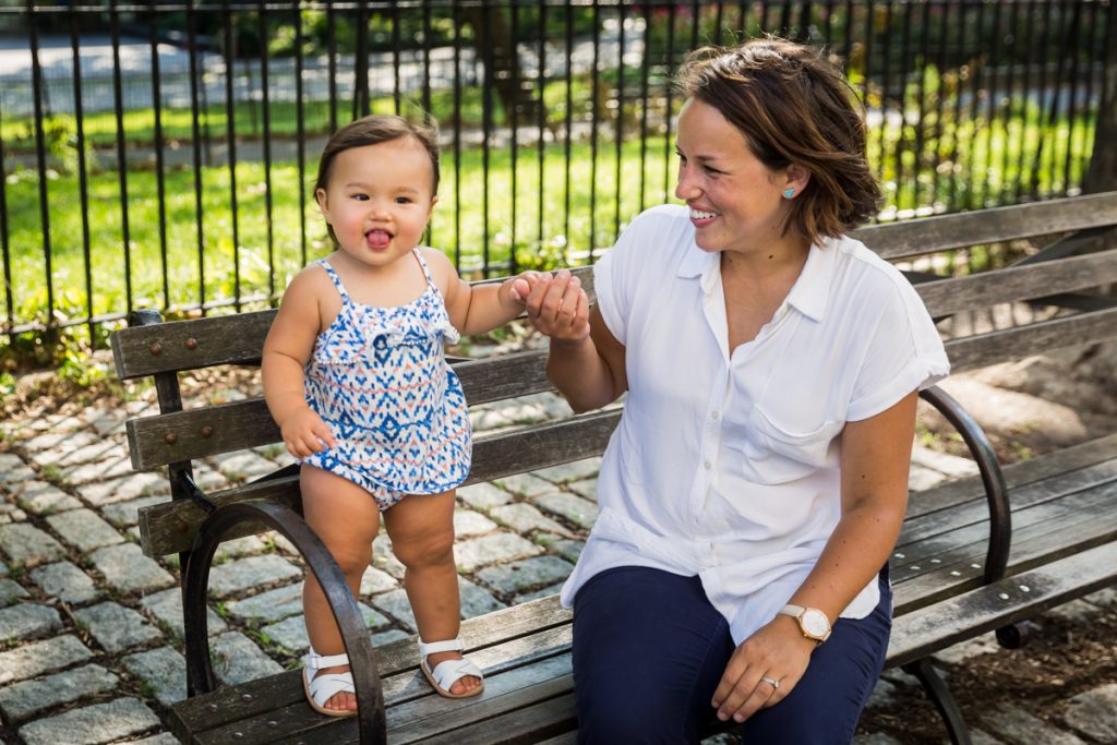 Mother holding baby girl standing on NYC bench