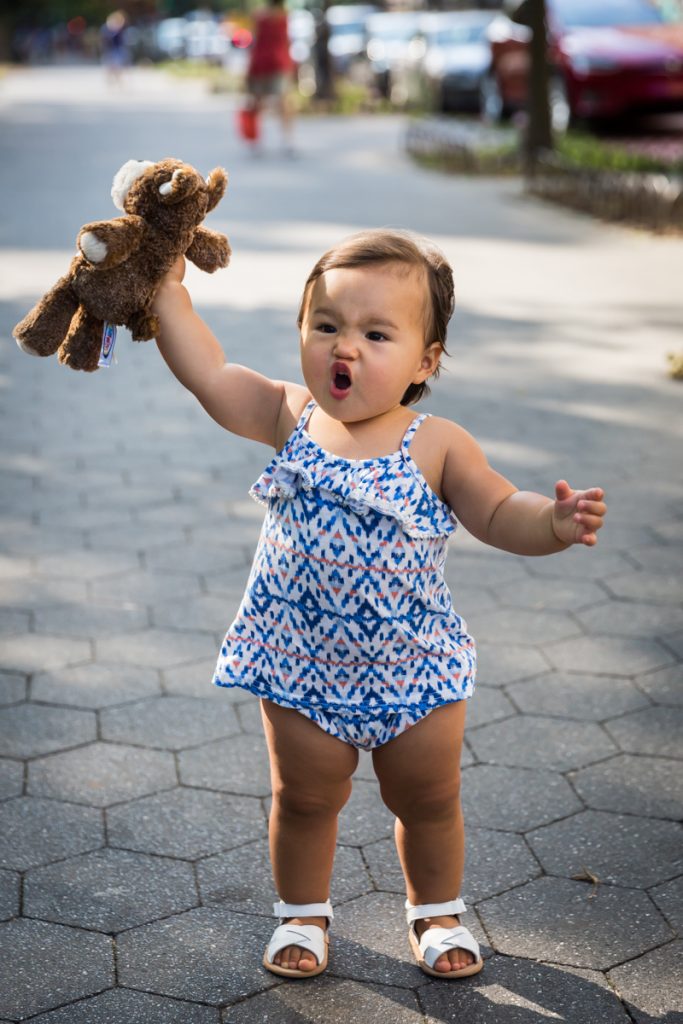 Little girl making funny face and holding up stuffed animal