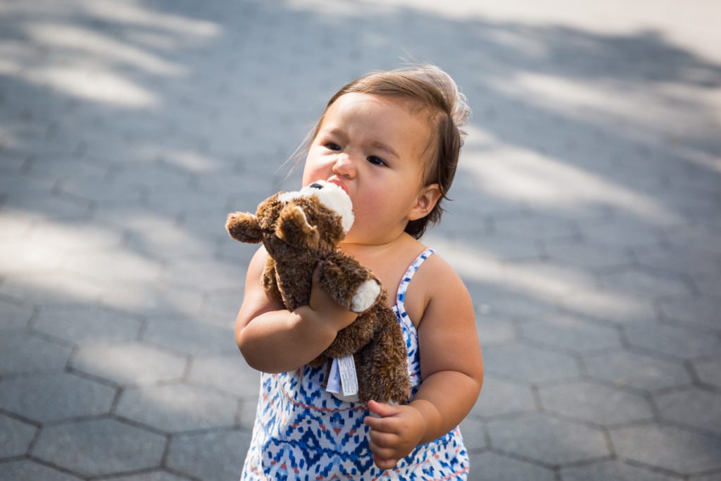 Baby girl eating stuffed animal
