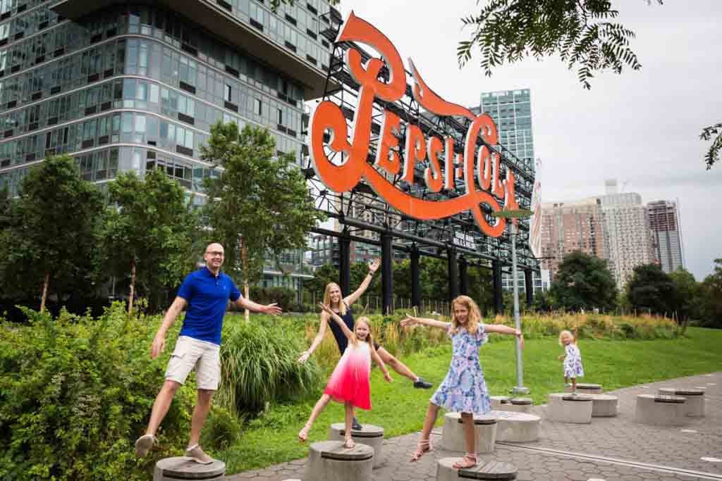 Family playing around on wooden stools in front of Pepsi Cola sign during a Gantry Plaza family portrait session