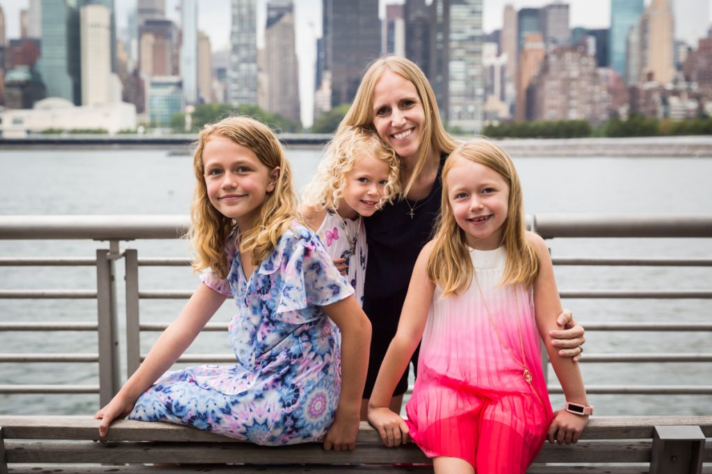 Mother and three daughters hugging on bench during a Gantry Plaza family portrait session