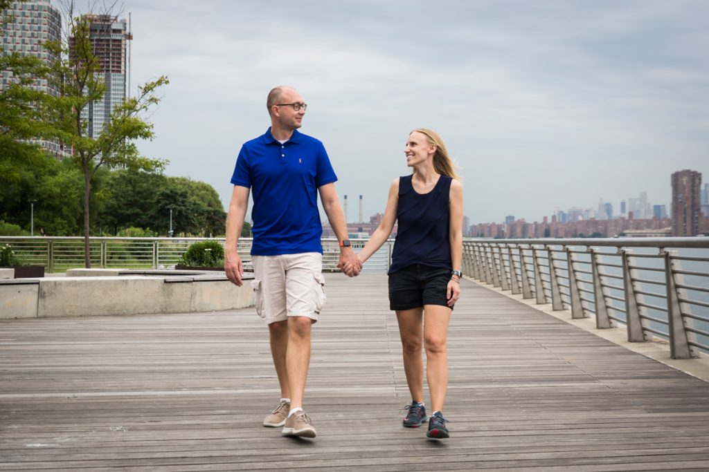 Couple holding hands and walking along Gantry Plaza State Park boardwalk