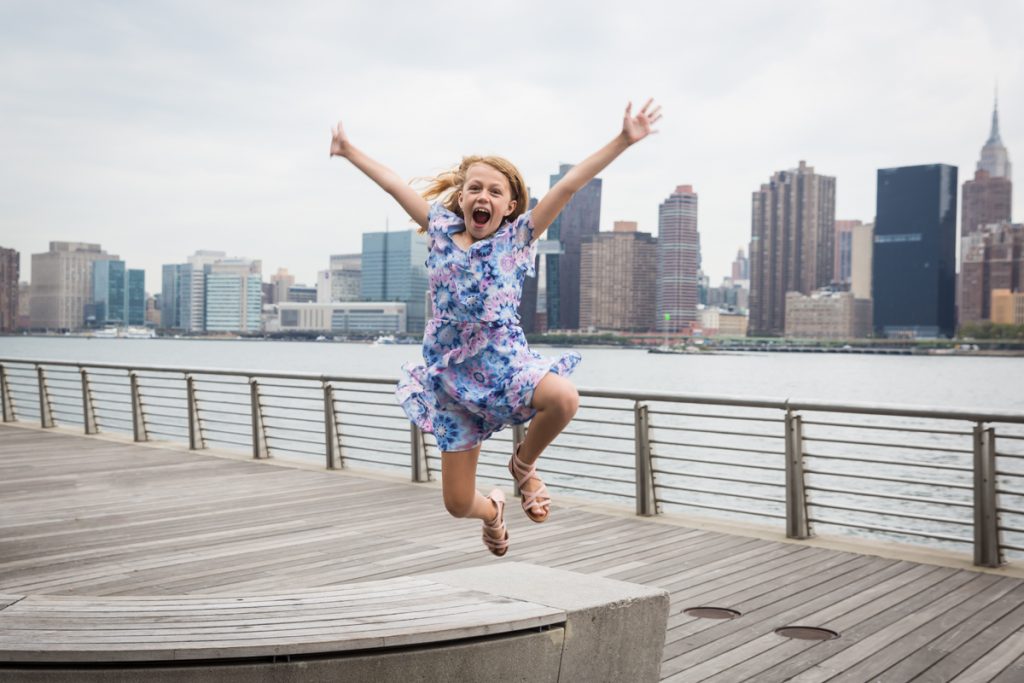 Little girl jumping on boardwalk during a Gantry Plaza family portrait session