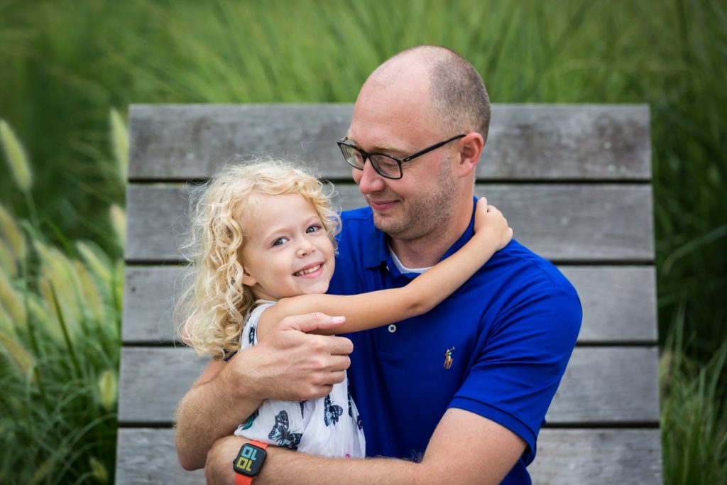 Blond haired girl hugging daddy on wooden chair