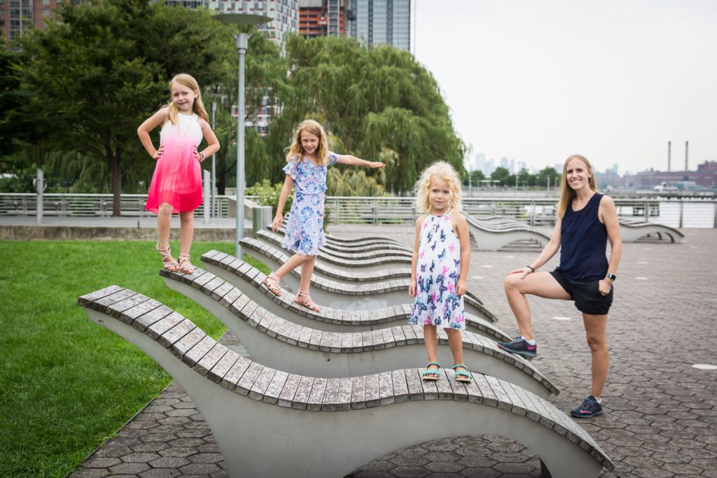 Mother and three daughters posed on curvilinear wooden lounge chairs
