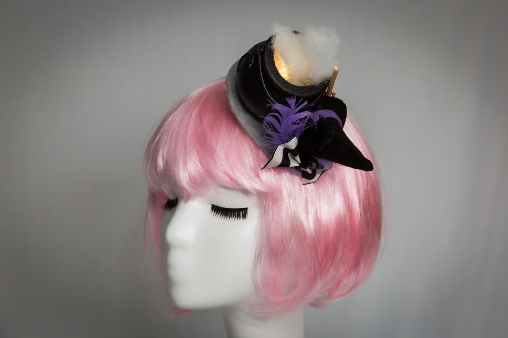 Pink haired mannequin wearing witch cauldron fascinator that lights up