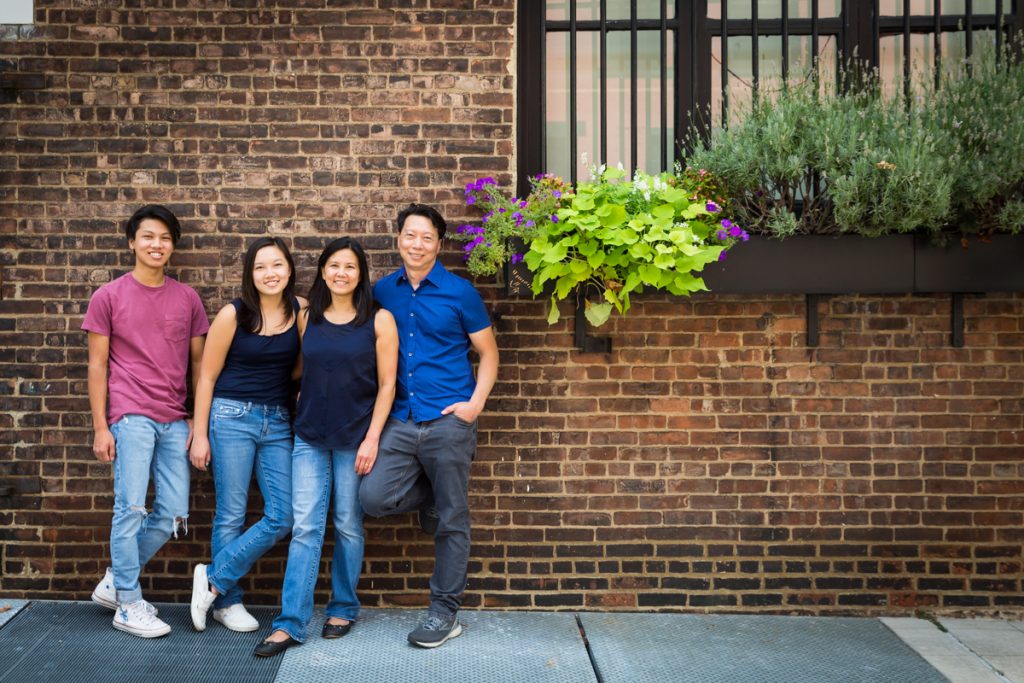 Family standing against brick wall with flowers in window box for an article on photo tips for older children