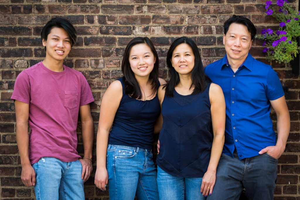 Asian family standing in front of brick wall