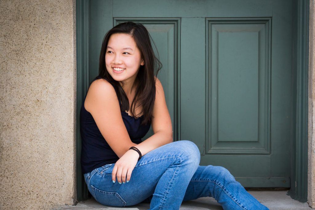 Young woman smiling while sitting in doorway in Washington Mews