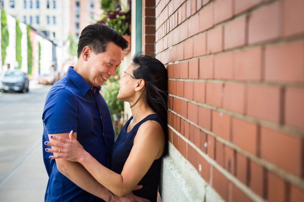 Asian couple hugging against brick wall