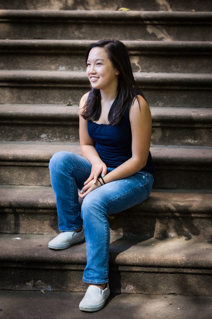 Young woman wearing jeans sitting on brownstone steps