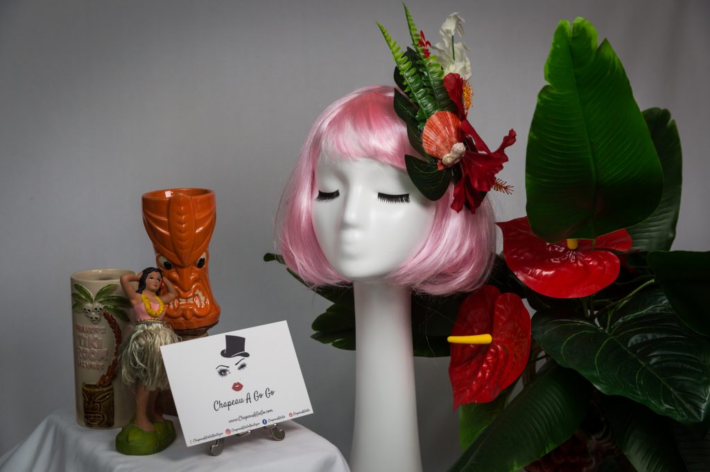 Pink haired mannequin wearing tiki flower hair clip with tiki mugs
