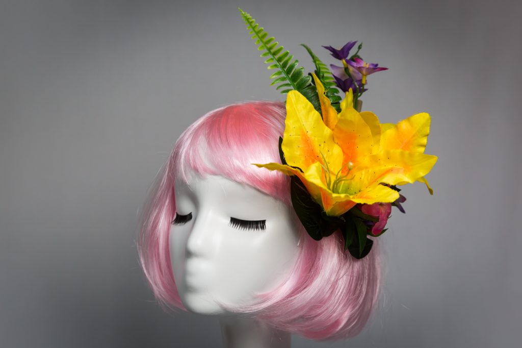 Pink haired mannequin wearing yellow tiki flower hair clip