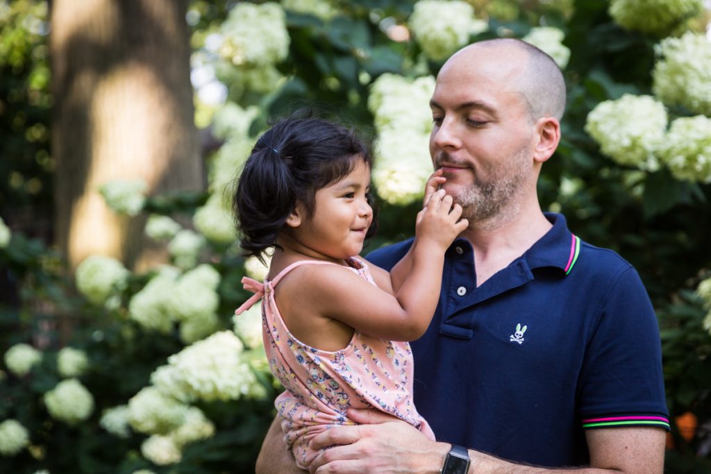 Father and little girl in front of hydrangea bush