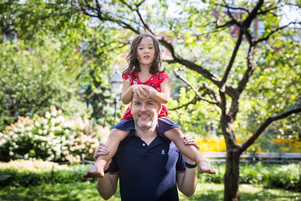 Father holding daughter on his shoulders during a Washington Square Park family portrait