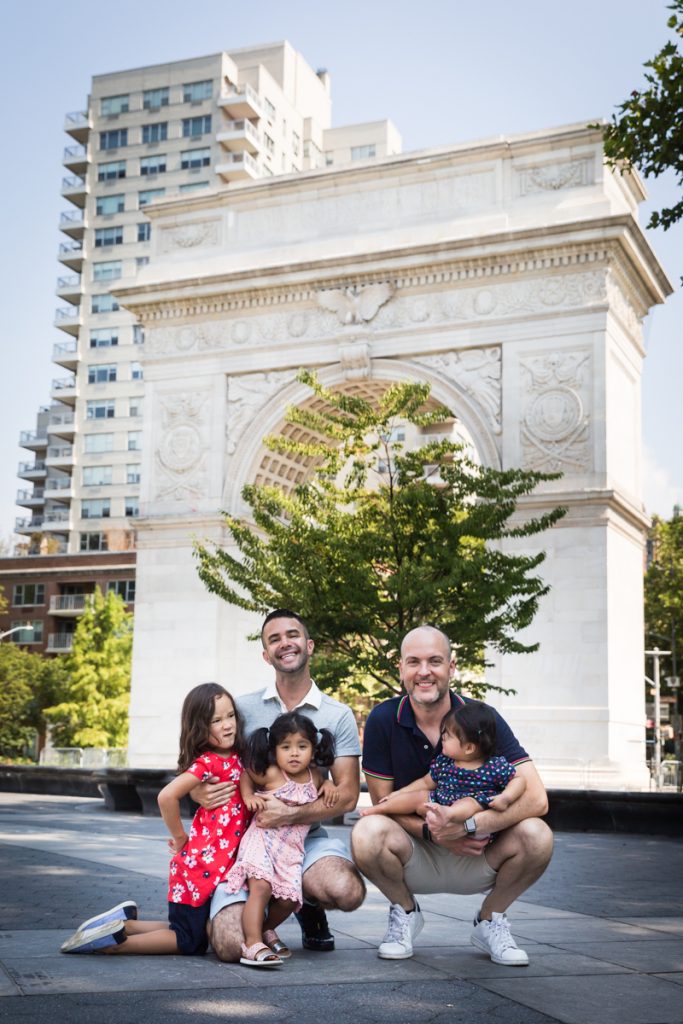 Two fathers and their three daughters in front of arch during a Washington Square Park family portrait