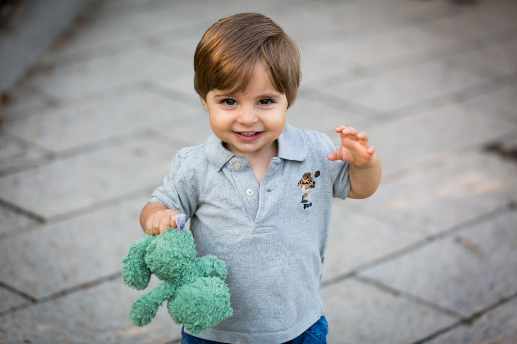 Little boy holding green stuffed animal in Hudson River Park