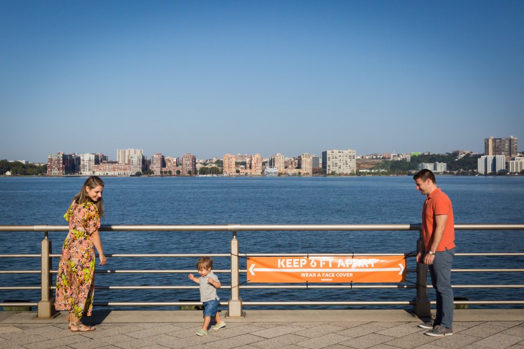 Parents and little boy standing in front of railing by Hudson River