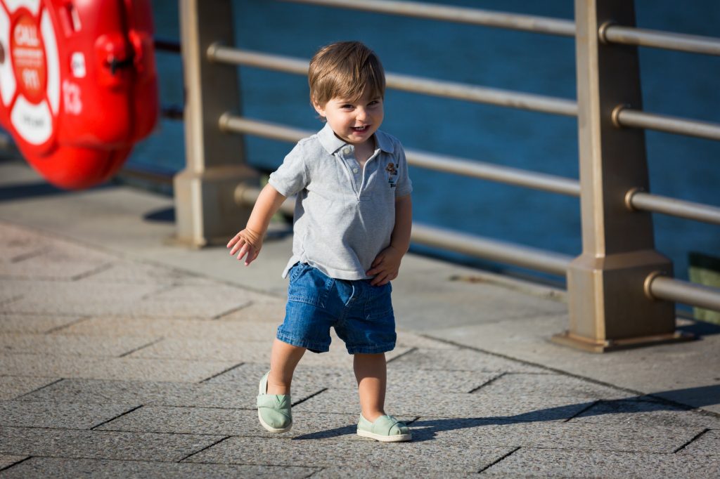 Little boy running in front of railing in Hudson River Park